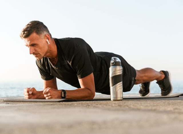 Fit Man που κάνει το Fordearm Plank σε εξωτερικούς χώρους, έννοια των καλύτερων ασκήσεων για τους άνδρες να χτίσουν δύναμη χωρίς εξοπλισμό
