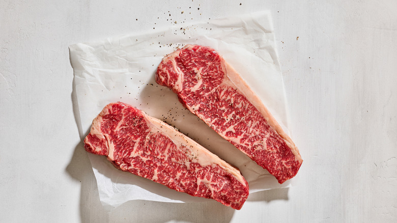 Δύο αυστραλιανά μπριζόλες βοδινού Wagyu σε λευκό κρεοπωλείο με φρέσκο πιπέρι Cracker