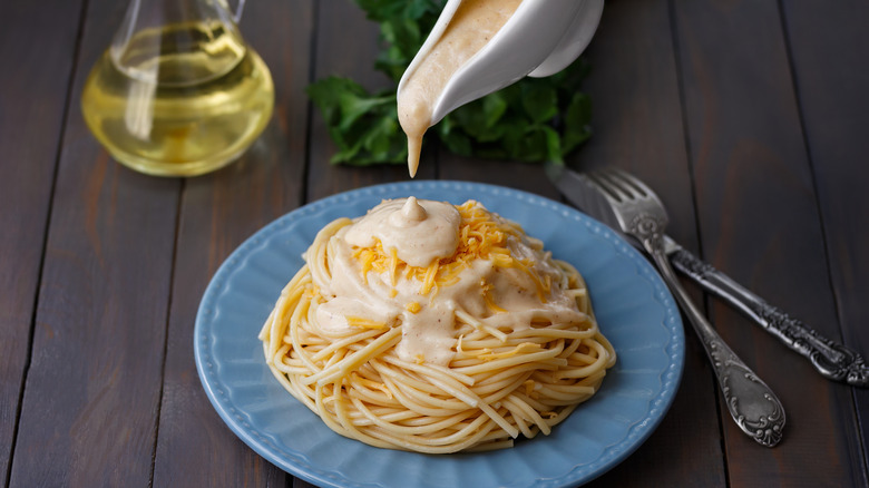 Πρόσωπο που ρίχνει τον Bechamel σε cheesy bucatini παρελθόν