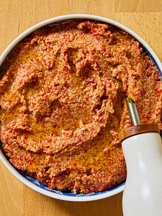 Ένα μπολ γεμάτο με Muhammara γεμάτο με ελαιόλαδο σε ξύλινη επιφάνεια